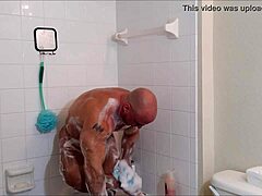 Мускулистый бодибилдер намыливается и смазывается в горячем душе